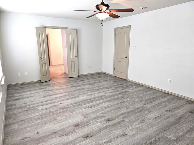 an empty room with wooden floor closet and windows