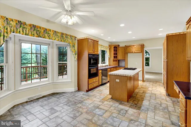 a large kitchen with kitchen island granite countertop a refrigerator a stove a sink a dining table and chairs with wooden floor