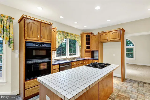 a kitchen that has a kitchen island wooden cabinets and stainless steel appliances