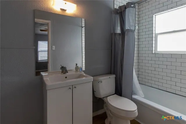 a bathroom with a toilet sink vanity tub and mirror