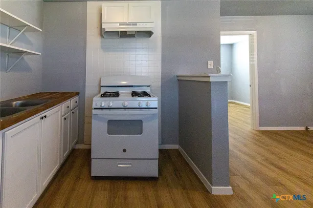 a kitchen with a stove oven and wooden floor
