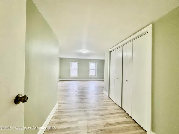 a view of a hallway with wooden floor and closet