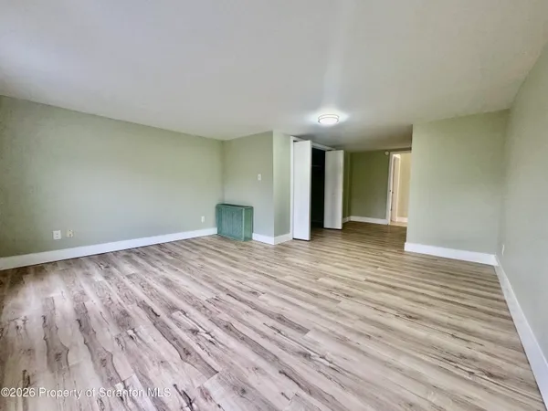a view of an empty room with wooden floor and closet