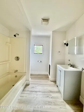 a bathroom with a tub sink and mirror