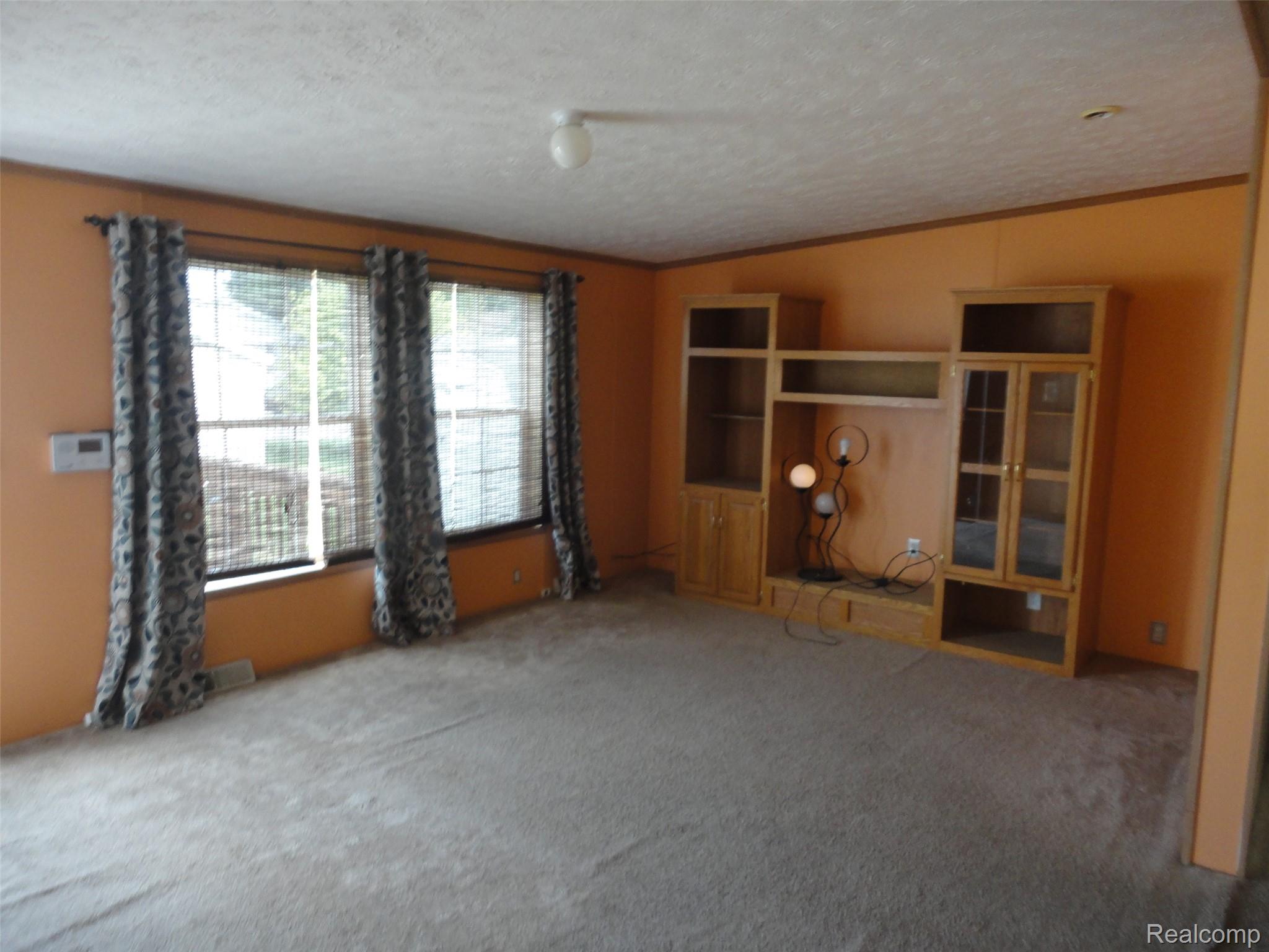 3954 Ryans Ridge Monroe, MI 48161 - Photo 7 of 28 Spacious living room featuring neutral carpet flooring, an integrated media center with glass-fronted cabinetry, and two large windows with window treatments