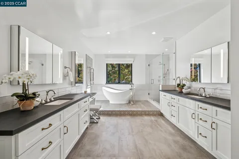a spacious bathroom with a double vanity sink a mirror a bathtub and window
