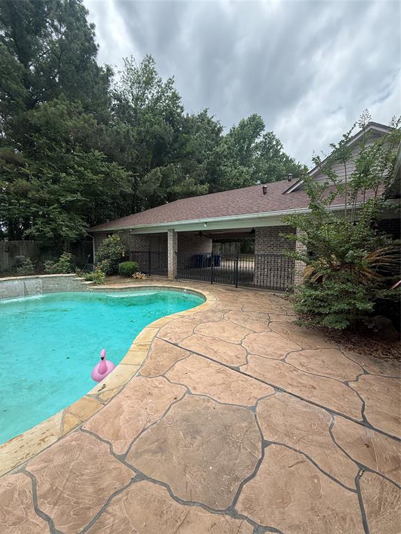 201 Woodhaven Drive Minden, LA 71055 - Photo 30 of 31 Expansive outdoor living area featuring a freeform swimming pool, stamped concrete patio, and a covered brick-columned porch with a shingle roof