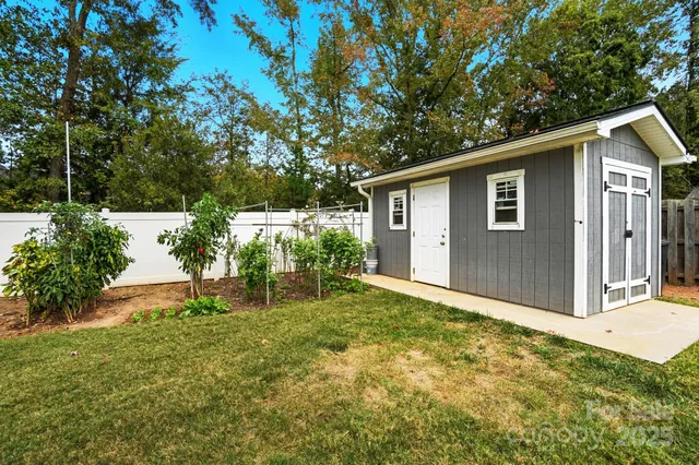 a backyard of a house with plants and large tree