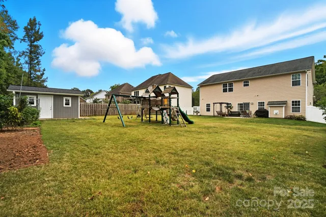 a view of a big house with a big yard and large trees