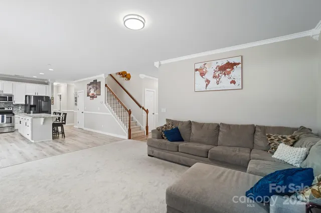 a living room with furniture and a dining table with kitchen view