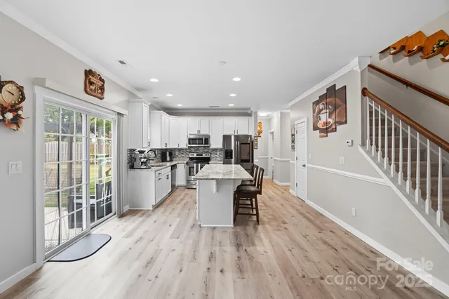 a dining room with stainless steel appliances furniture large window and wooden floor