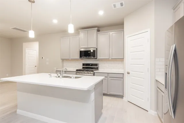 a kitchen with kitchen island a sink stainless steel appliances and cabinets
