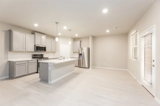 a kitchen with stainless steel appliances granite countertop a refrigerator oven a sink dishwasher and a stove top oven with white cabinets