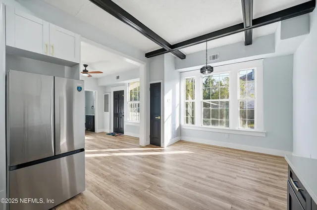 an empty room with wooden floor fan and windows
