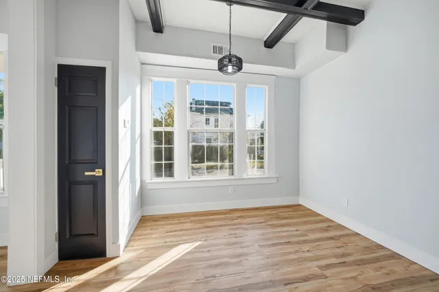 a view of an empty room with a window and wooden floor