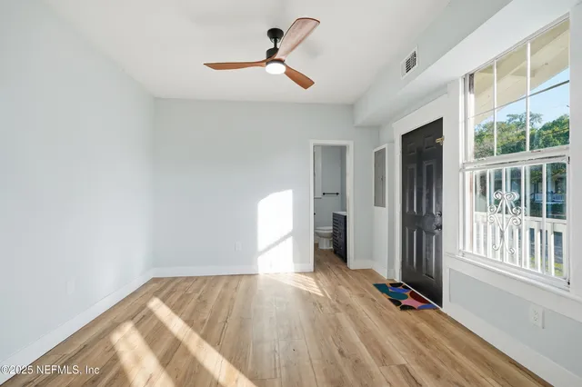 a view of empty room with wooden floor and fan