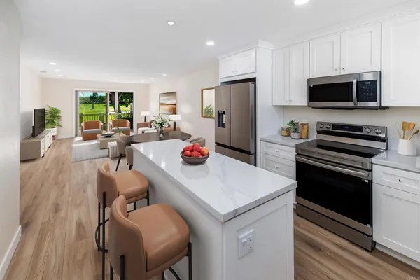 a kitchen that has a refrigerator a stove a microwave and dining table with wooden floor