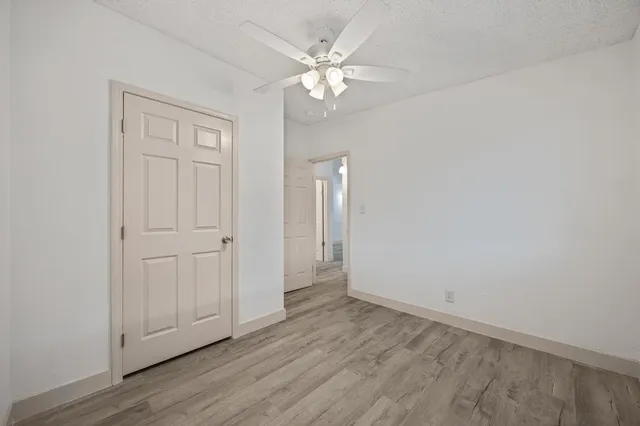an empty room with wooden floor and ceiling fan