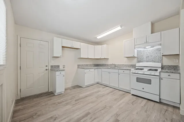 a kitchen with cabinets wooden floor and stainless steel appliances