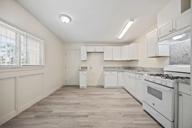 a kitchen with granite countertop white cabinets and white appliances