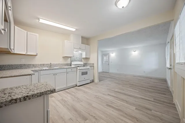 a kitchen with granite countertop a sink cabinets and wooden floor