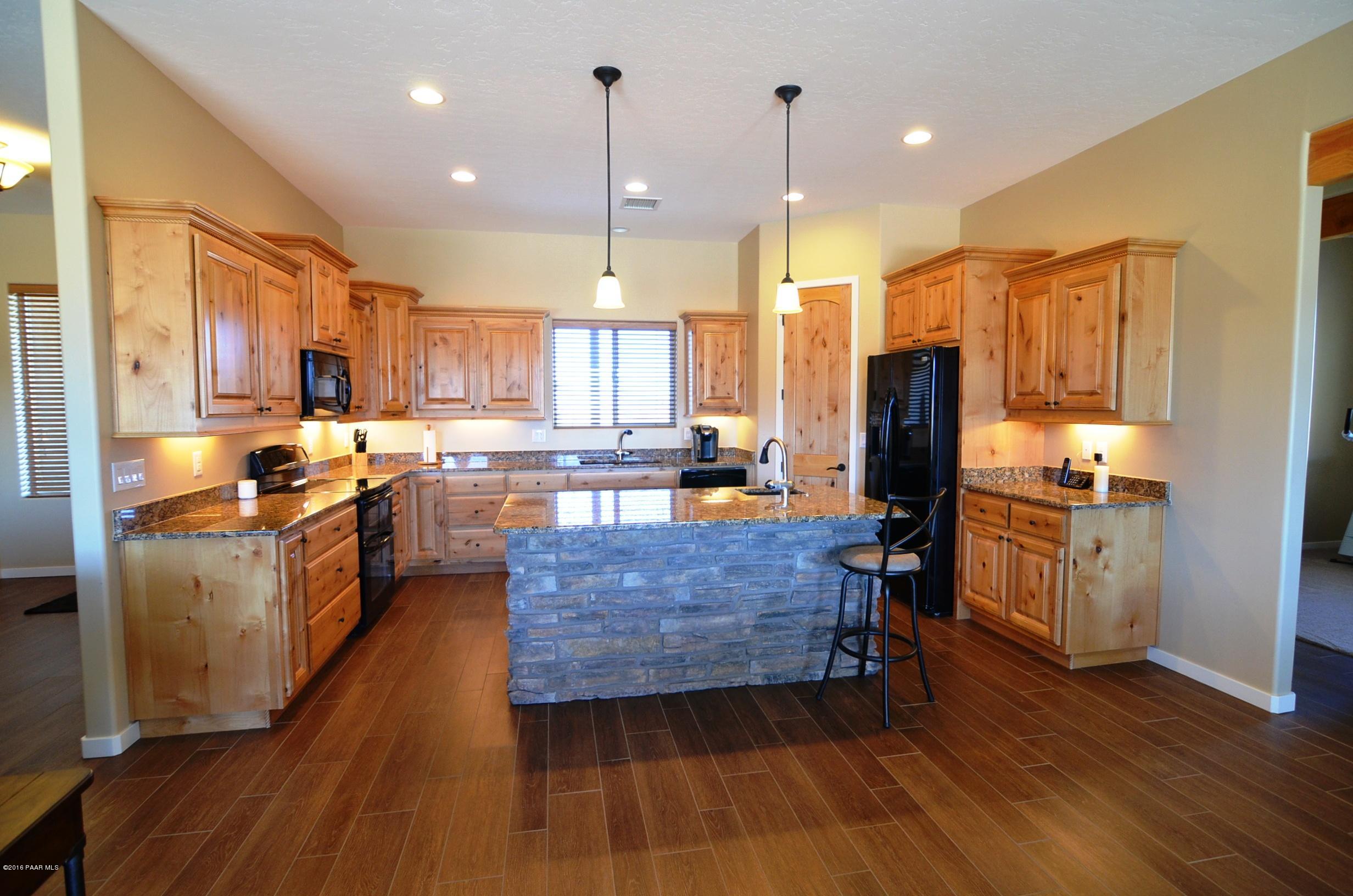 9474 Dows Ranch Road Prescott Valley, AZ 86315 - Photo 4 of 55 a kitchen with stainless steel appliances kitchen island granite countertop a stove a refrigerator a oven a sink a stove and a wooden floors