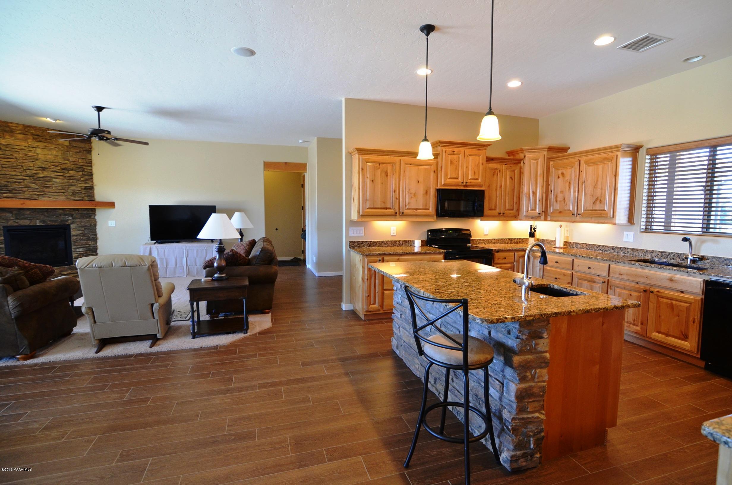 9474 Dows Ranch Road Prescott Valley, AZ 86315 - Photo 50 of 55 a kitchen with stainless steel appliances granite countertop a stove top oven a sink dishwasher a dining table and chairs with wooden floor