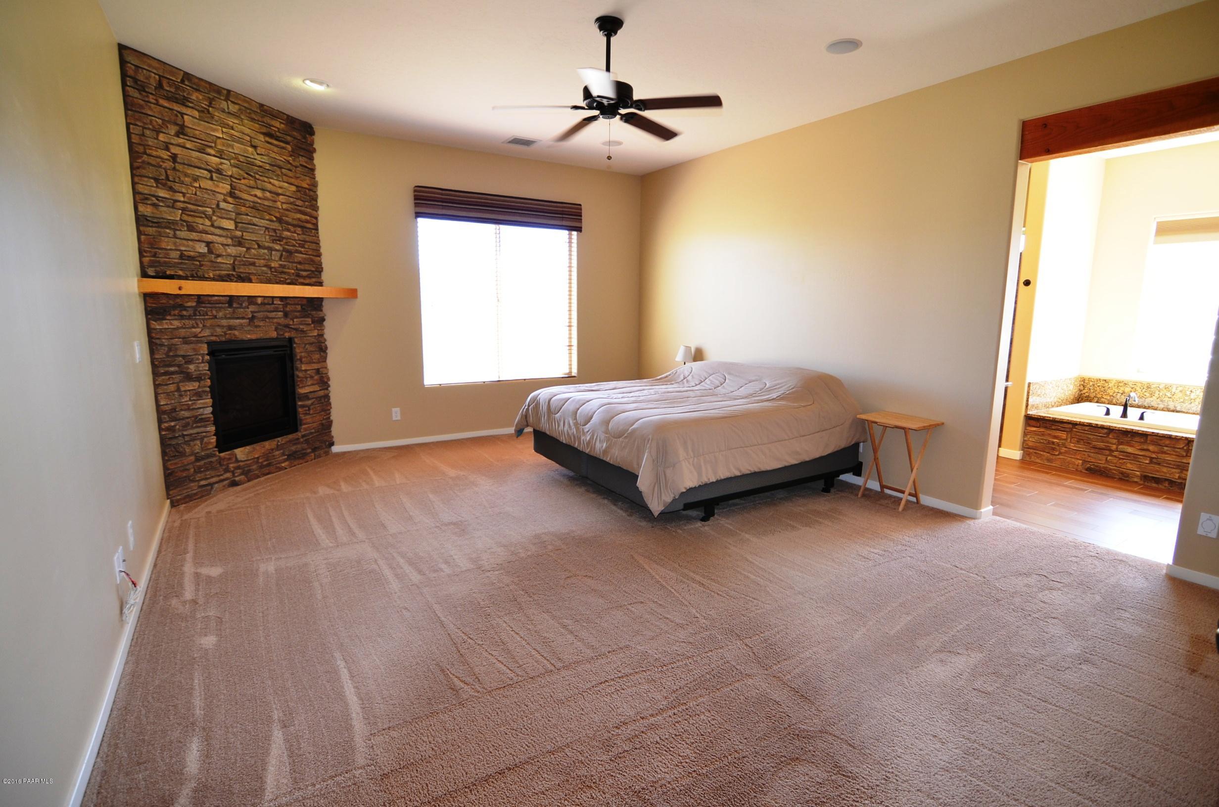 9474 Dows Ranch Road Prescott Valley, AZ 86315 - Photo 52 of 55 a spacious bedroom with a bed and a fireplace