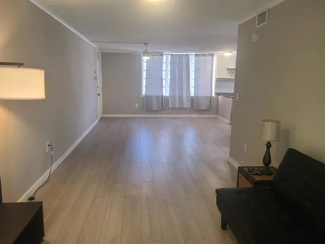 a view of empty room with wooden floor and fan