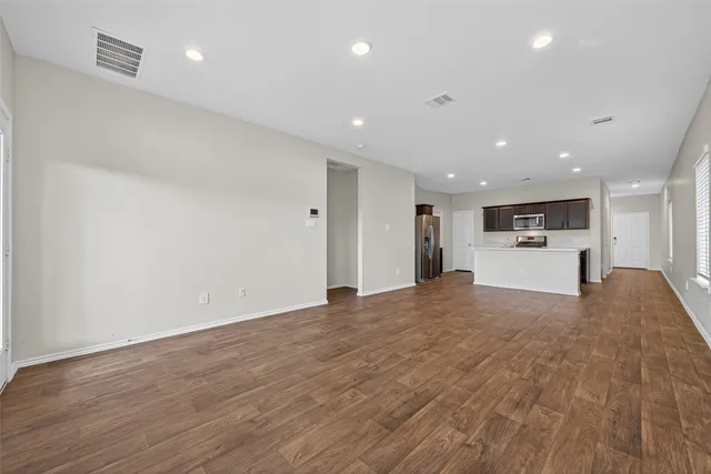 a view of large empty room with kitchen