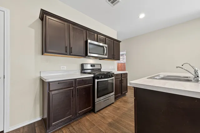 a kitchen with stainless steel appliances granite countertop a sink and a stove top oven with wooden floor