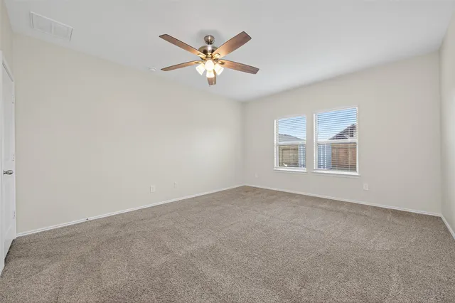 a view of an empty room with chandelier fan and fire place