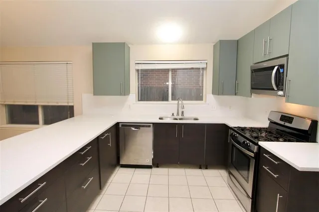 a large white kitchen with a sink and chandelier