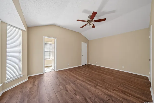 a view of empty room with wooden floor and fan