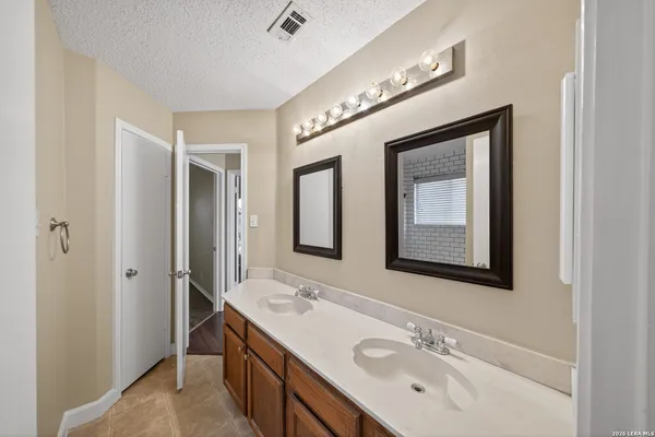 a bathroom with a double vanity sink mirror and next to a window