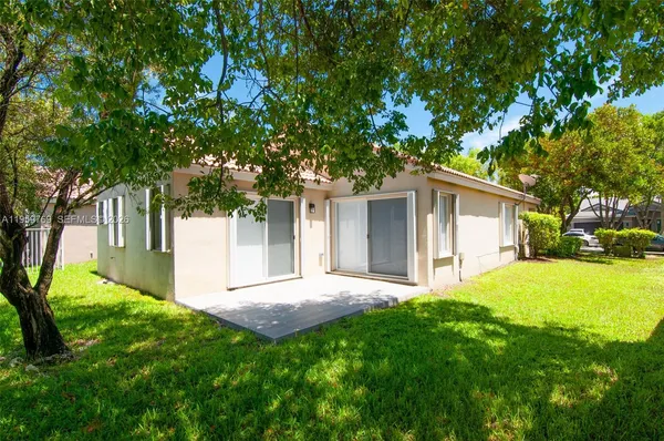 a view of a house with backyard and a tree