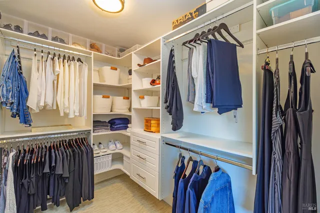 a view of walk in closet with clothes and shoes