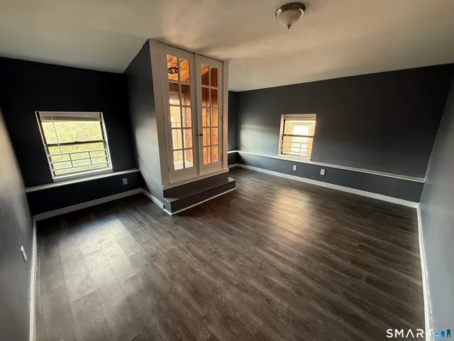 an empty room with wooden floor and windows