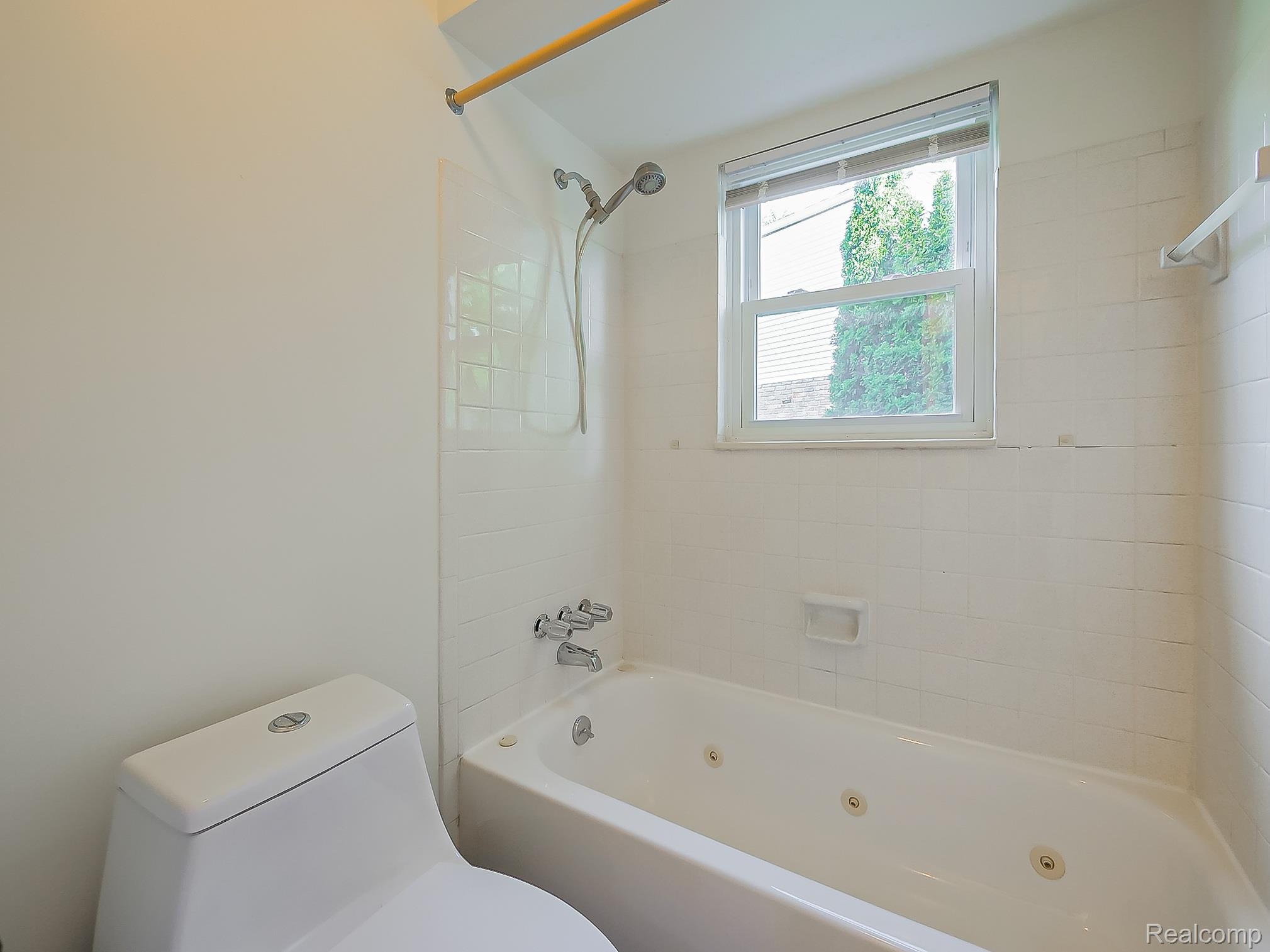 42195 Park Ridge Road Novi, MI 48375 - Photo 34 of 52 Bathroom featuring a white toilet, white tiled walls, a window with blinds, and a white bathtub with jetted features