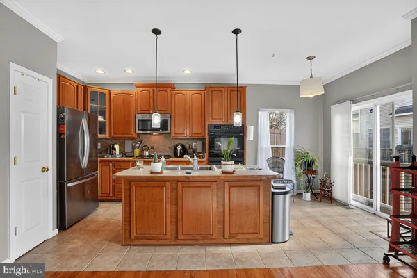 a kitchen with stainless steel appliances granite countertop a refrigerator a sink dishwasher a stove and a dining table with wooden floor