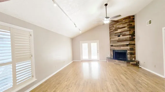 a view of empty room with a fireplace and wooden floor