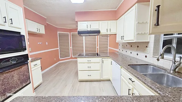 a kitchen with granite countertop a sink stove and cabinets