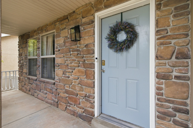 2223 North Pointe Meadow Loop Lehi, UT 84048 - Photo 4 of 56 Front entry featuring a light blue door with panel detailing, stone veneer siding, and a covered porch