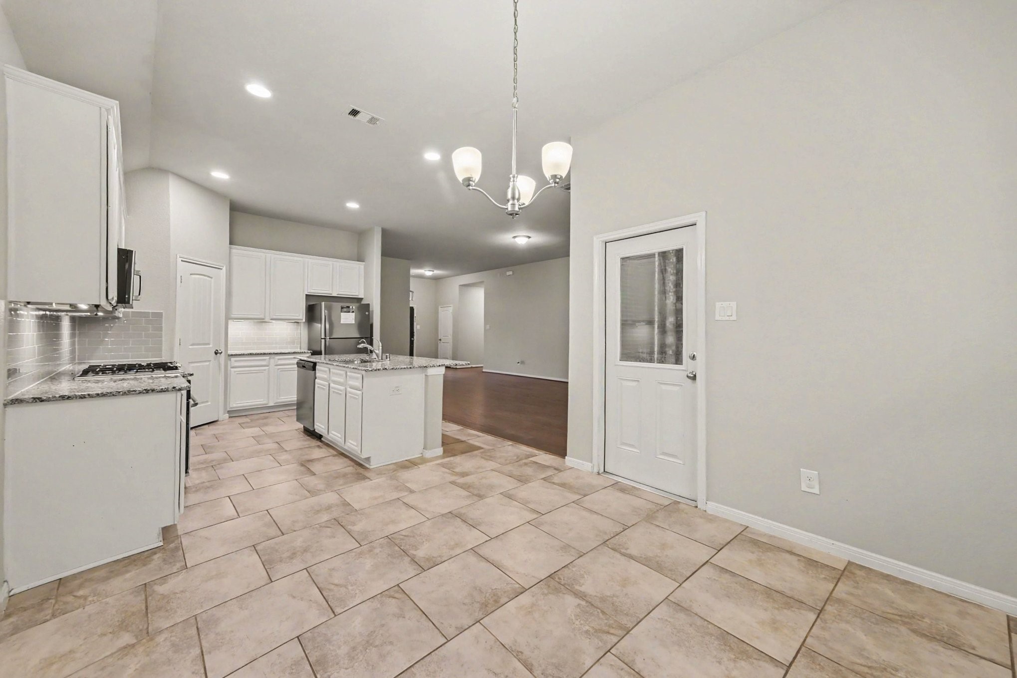 24554 Grayson Falls Lane Spring, TX 77389 - Photo 11 of 27 a open kitchen with a sink dishwasher a refrigerator and white cabinets with wooden floor