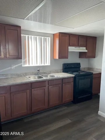a kitchen with granite countertop a sink cabinets and wooden floor