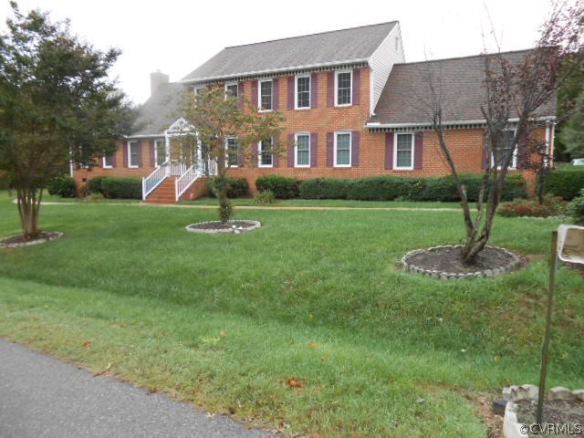 a front view of a house with a yard and tree