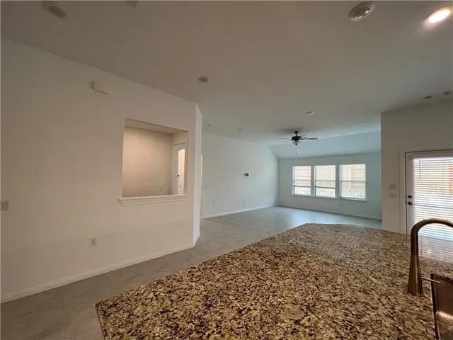 a large kitchen with a large counter top a stove a counter space and cabinets