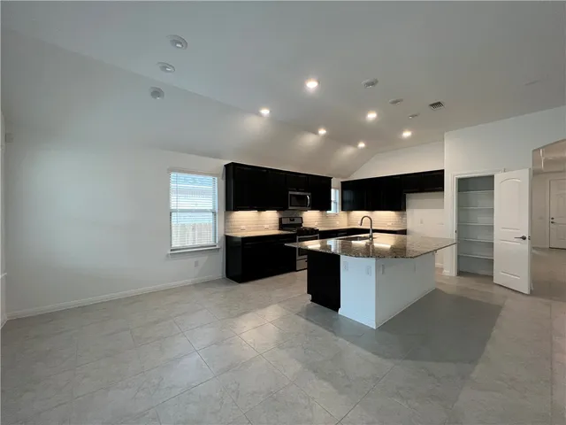 a view of an empty room with a window and a kitchen