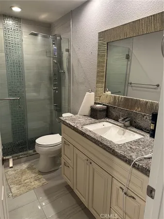 a bathroom with a granite countertop sink toilet and shower