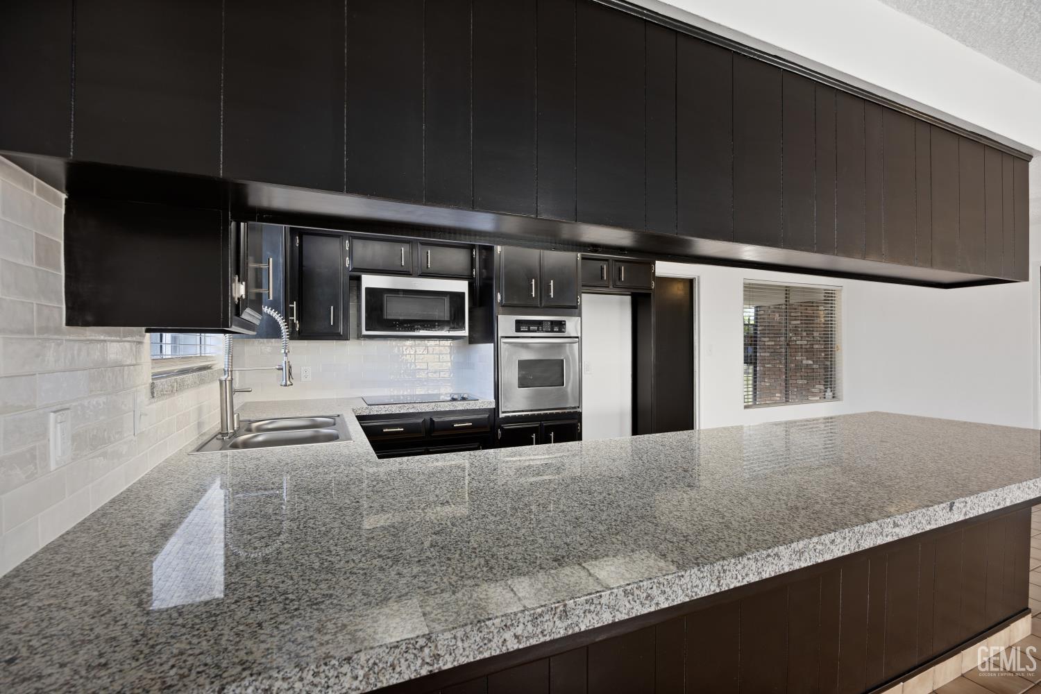 Undisclosed Address Bakersfield, CA 93312 - Photo 19 of 30 a kitchen with stainless steel appliances kitchen island granite countertop a stove a sink and a microwave